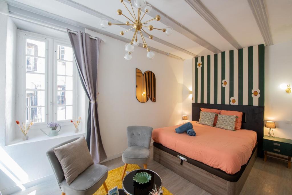 a bedroom with a bed and a chair and a tub at Suite Lyséa - Balnéothérapie au Coeur d'Annecy in Annecy