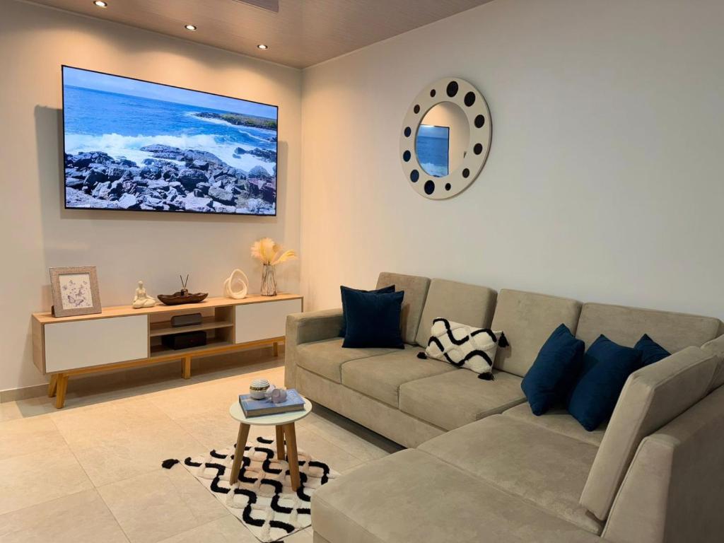 a living room with a couch and a tv on the wall at Suite Rosedelco in Puerto Villamil
