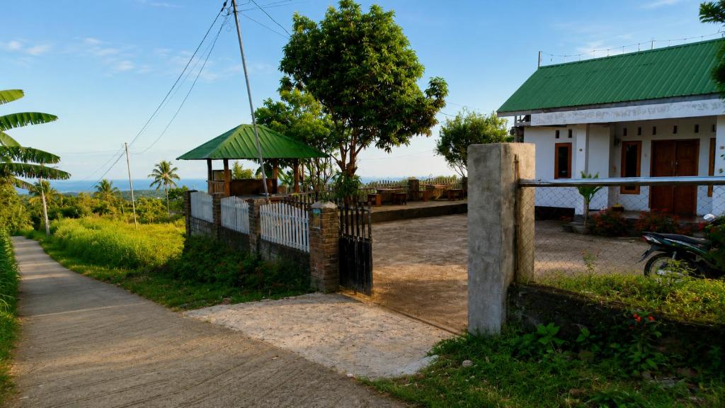 a fence in front of a house with a tree at Sunset Homestay in Sapit