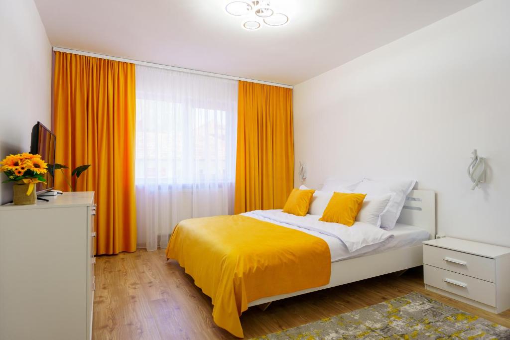a bedroom with an orange and white bed and a window at Joy Apartament in Nehoiu