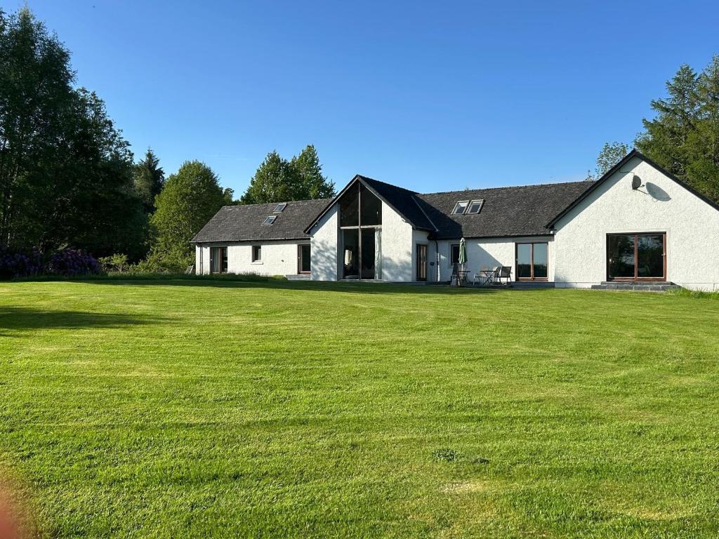 a large white house with a large grass yard at Powdermills B & B in Inveraray
