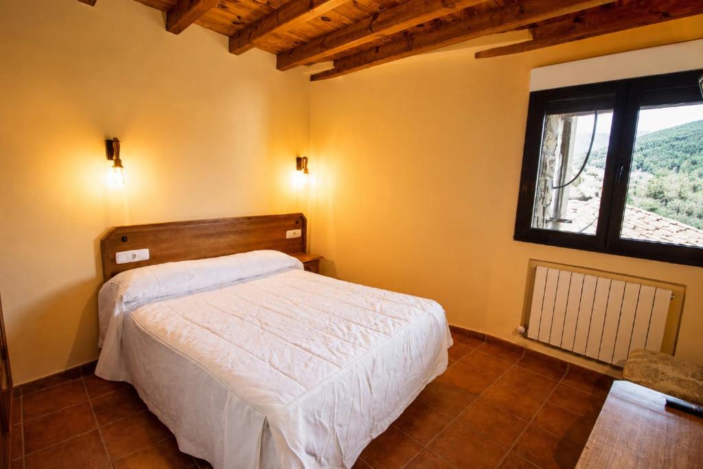 a bedroom with a white bed and a window at La Guarida de la Lleira in Ferreras de Arriba