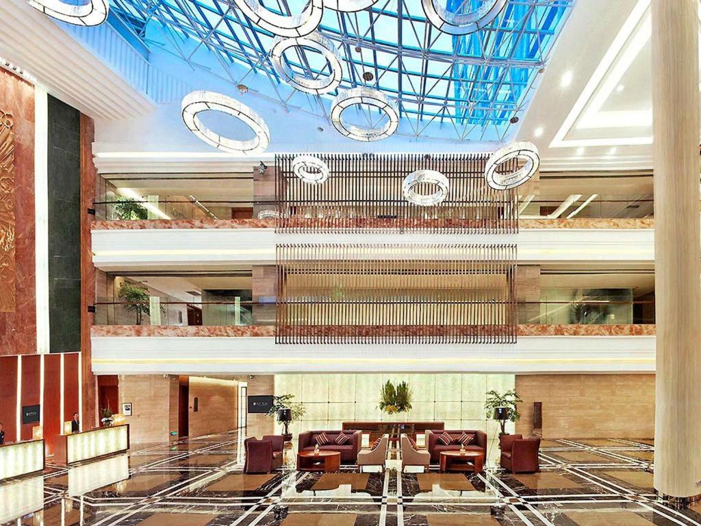 a lobby with couches and a large ceiling at Pullman Xiamen Powerlong in Xiamen
