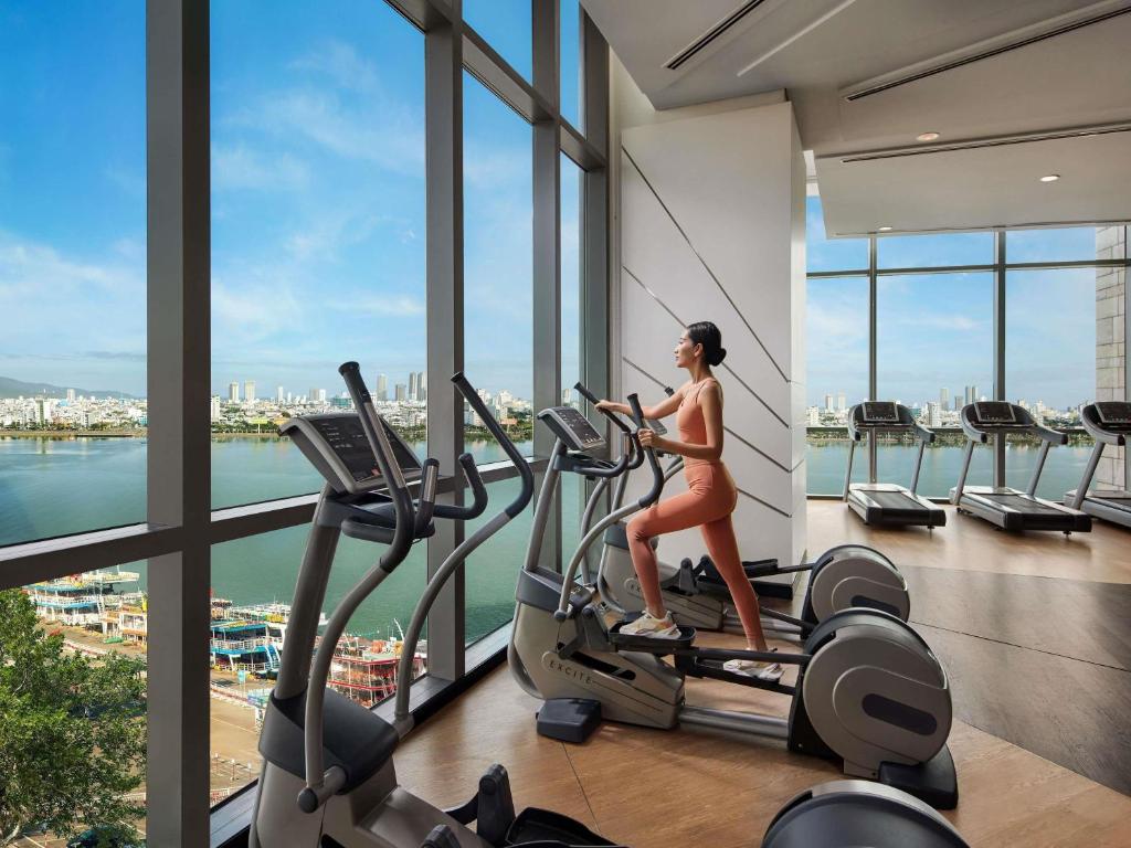 A cardio area beside tall windows overlooking the riverfront and city.