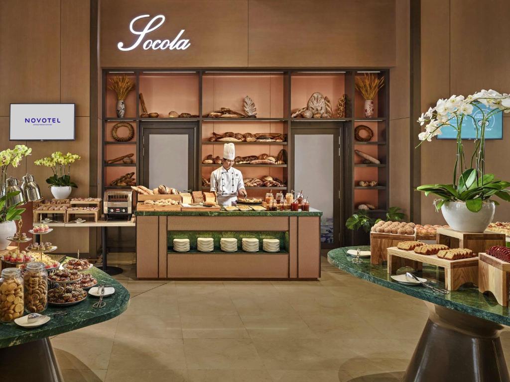 A bakery-style buffet station with breads, pastries, cookies and a staff member.