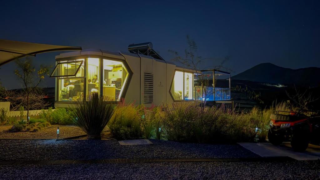ein winziges Haus, das nachts in einem Garten steht in der Unterkunft Capsule Mountain in Lagunillas