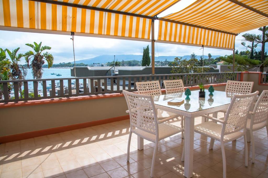 a table and chairs on a balcony with a view of the water at Villa Tommi a due passi dal mare in Fontane Bianche