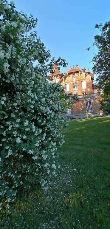 a large house behind a bush with white flowers at Villa du Sauzin in Cronat