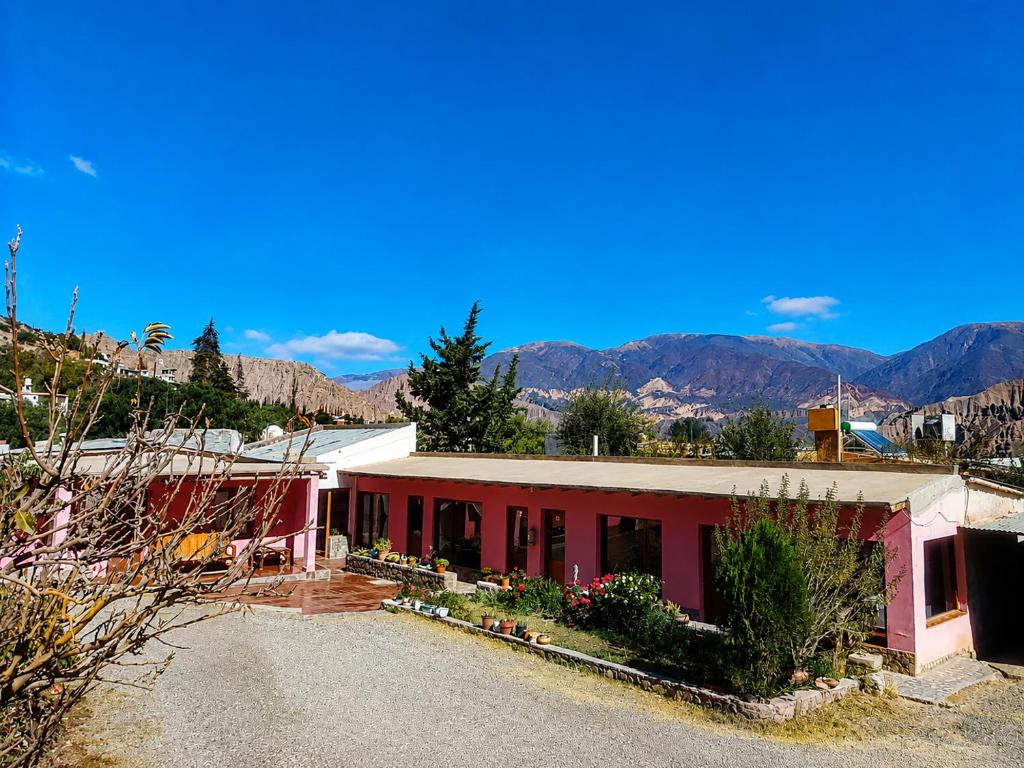 a red building with mountains in the background at Posada Yacoraite Tilcara in Tilcara