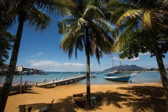 a beach with palm trees and a boat in the water at Studio 187 in Rio das Ostras