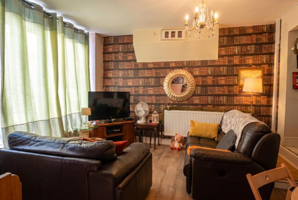 a living room with two leather couches and a television at Vintage 2-bed flat with free parking in Measham in Measham