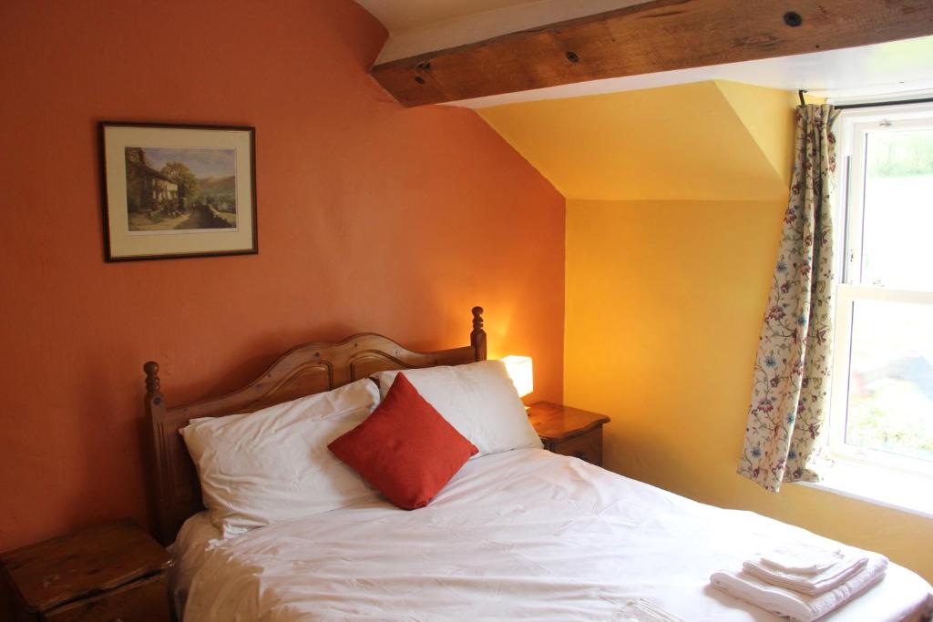 a bedroom with a bed with white sheets and a window at Half Moon Inn in Llanthony