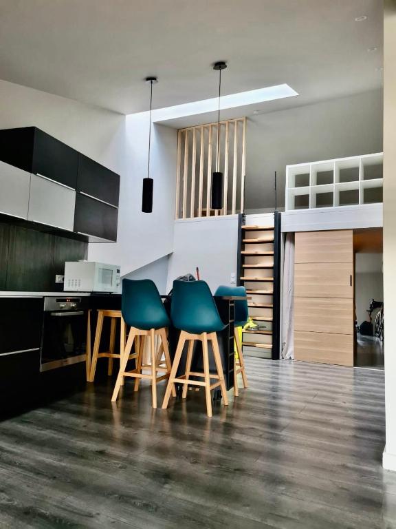 a kitchen with green chairs and a kitchen table at Le refuge médiéval - Appartement climatisé perché sous les toits de Billom in Billom