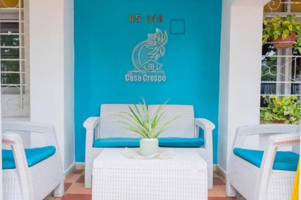 a room with three wicker chairs and a blue wall at Casa Crespo in Cartagena de Indias