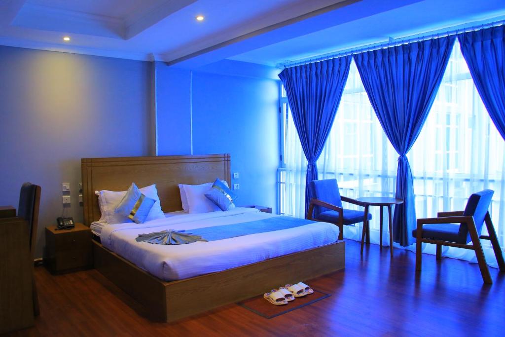 a blue bedroom with a bed and a table and chairs at Burqito International Hotel in Āwasa