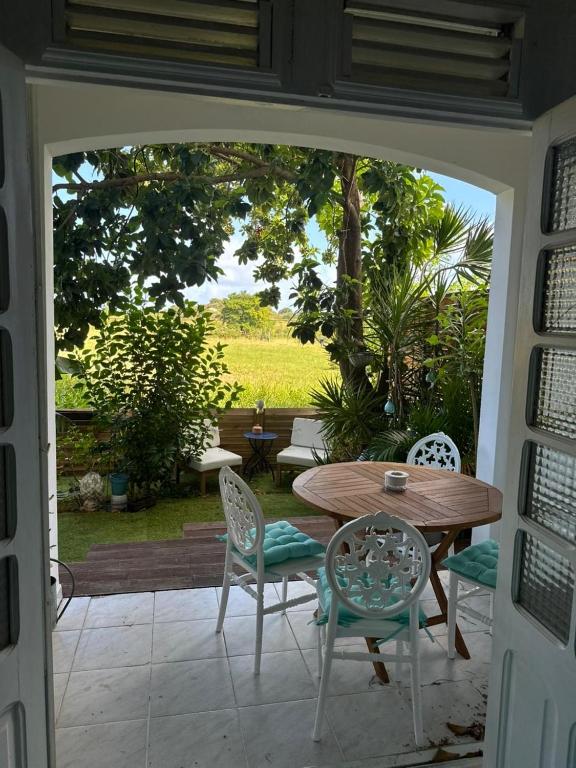 a patio with a table and chairs and a view of a field at Le Jardin Secret in Le Vauclin
