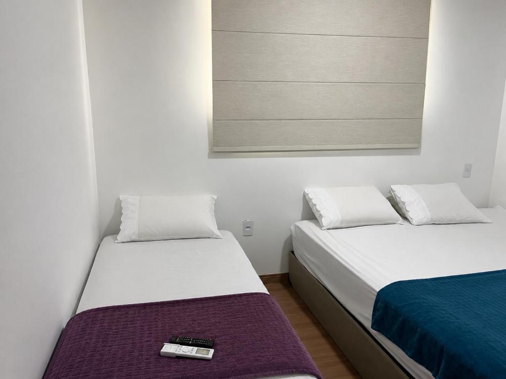 two beds in a room with a remote control on the bed at 7 min de Cabo Frio AP LISBOA in São Pedro da Aldeia