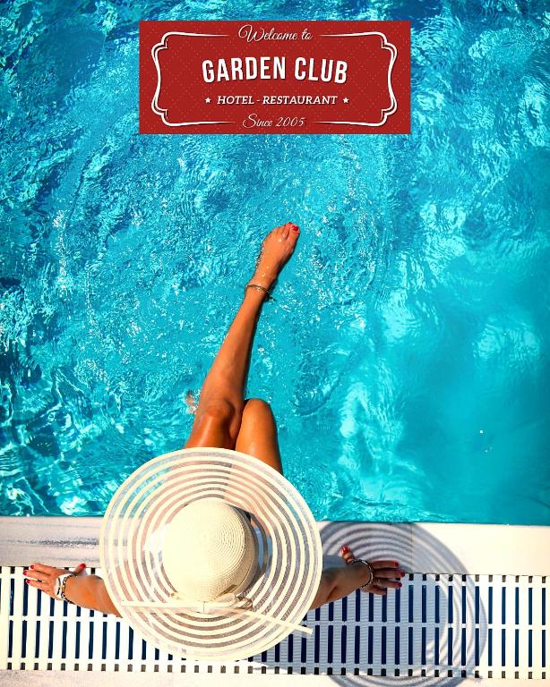 a woman in a hat laying in a swimming pool at GARDEN Club - Hotel & Restaurant - FREE Outdoor Pool & Parking in Braşov