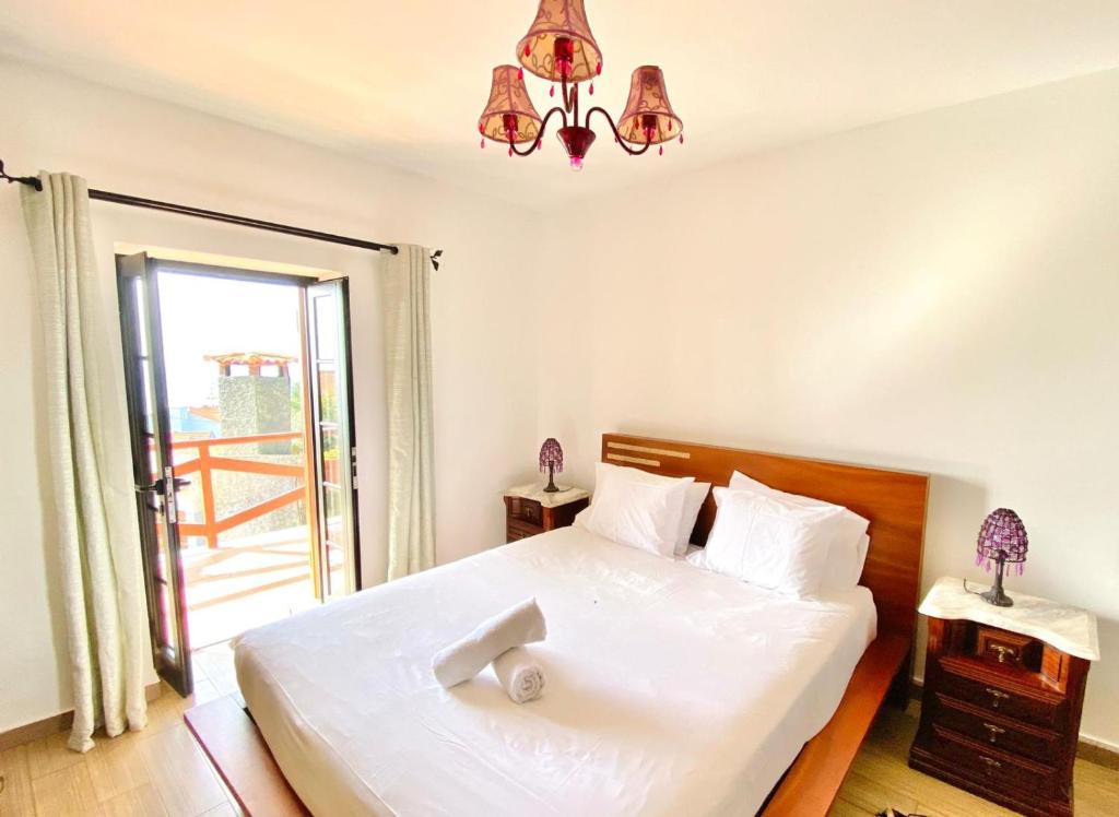 a bedroom with a large white bed with a window at O Cantinho do Pargo in Ponta do Pargo