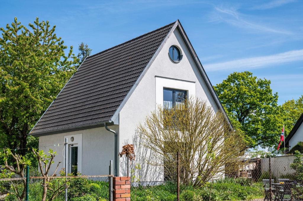 a small white house with a black roof at Sonne in Diedrichshagen