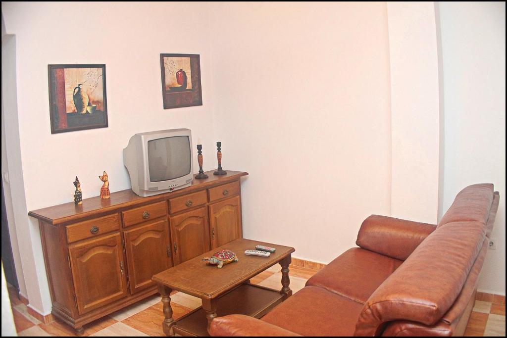 a living room with a couch and a tv on a dresser at Apartamento San José Conil in Conil de la Frontera