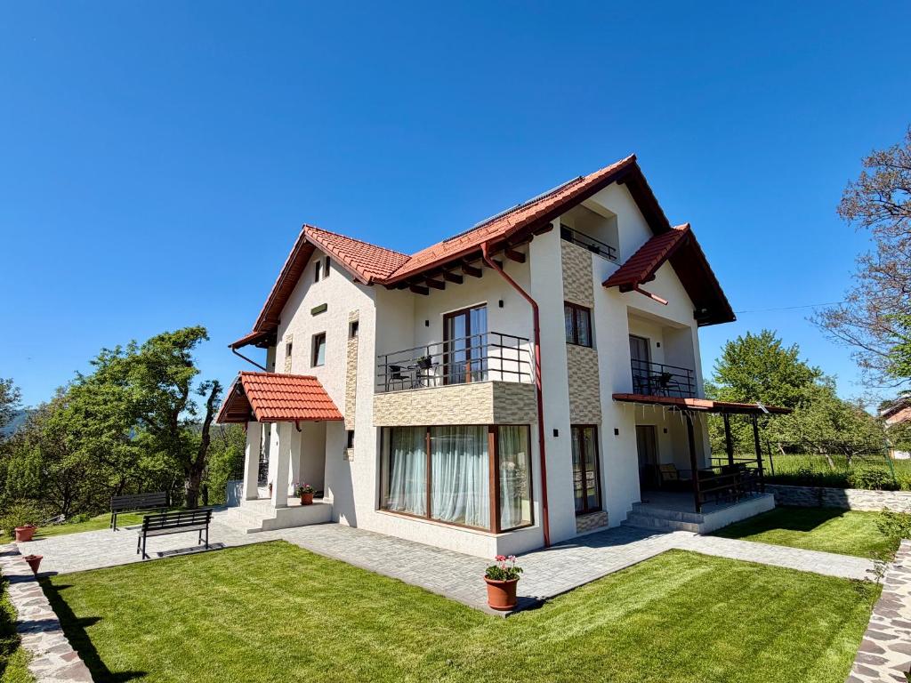 a white house with a bench on a lawn at Casa Cențiu II in Bran