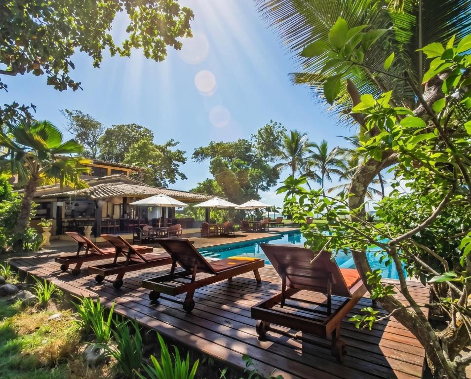 a deck with chairs and a pool at a resort at Pousada Villa Bianca in Arraial d'Ajuda