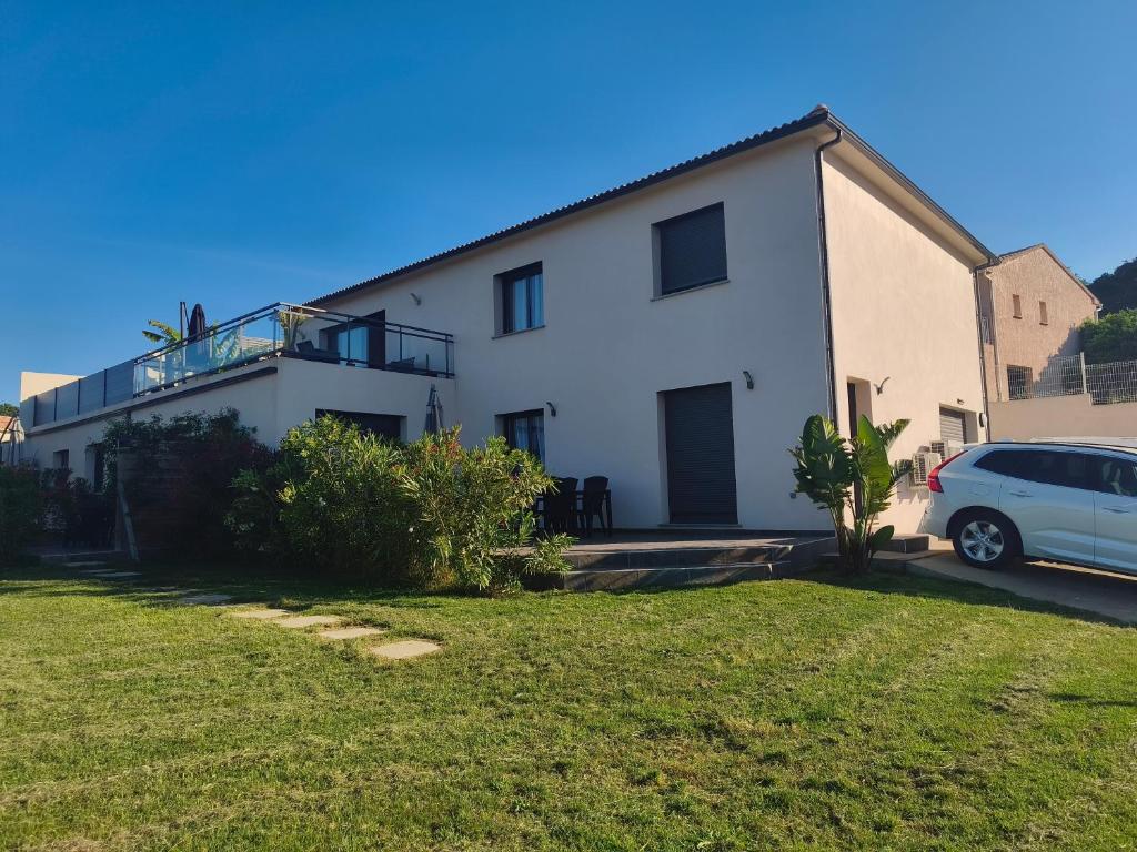 a white house with a car parked in front of it at Doume et Coco T1 30M2 Vue mer in Taglio-Isolaccio