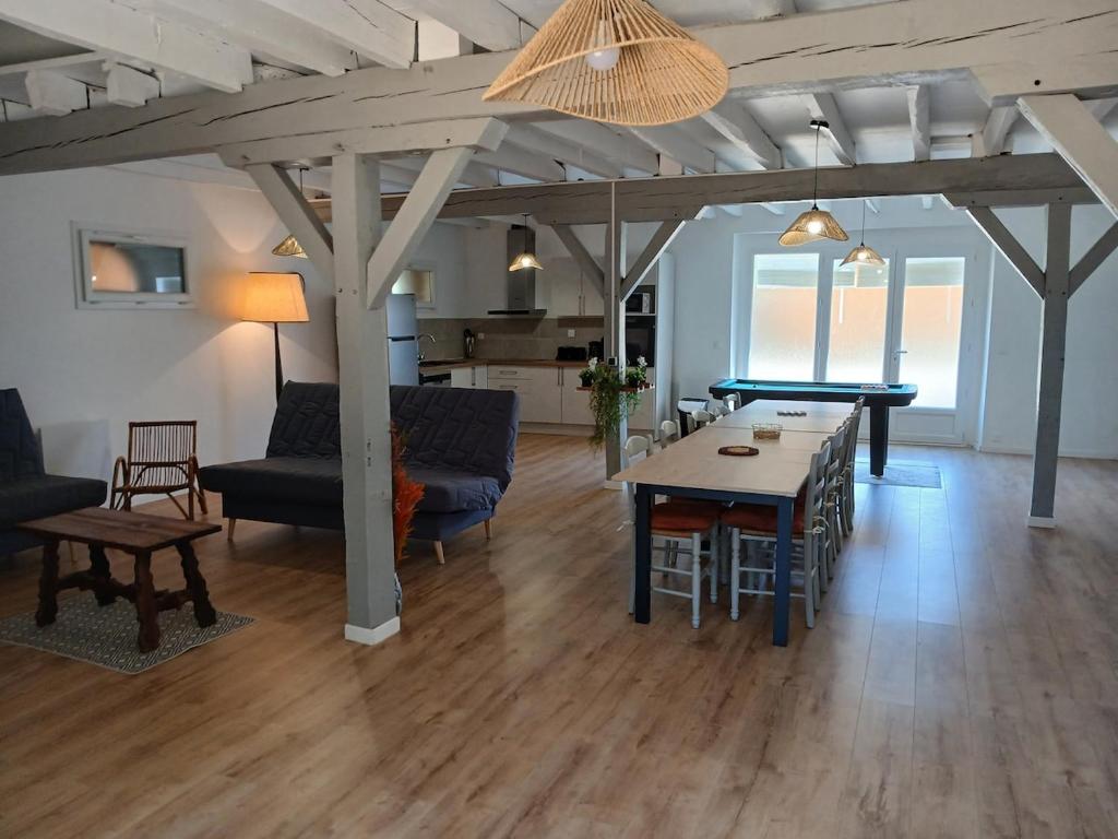 a living room with a ping pong table and a dining room at La Grange Landaise in Laglorieuse