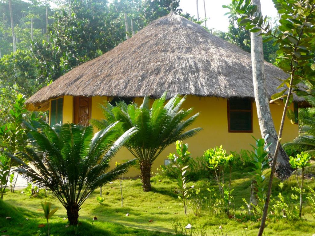 a small yellow house with a thatched roof at Ankobra Beach Resort in Axim
