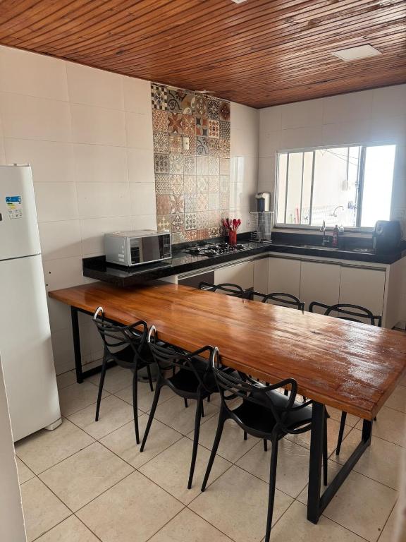 a kitchen with a wooden table with chairs and a microwave at Palmeira House in Formosa