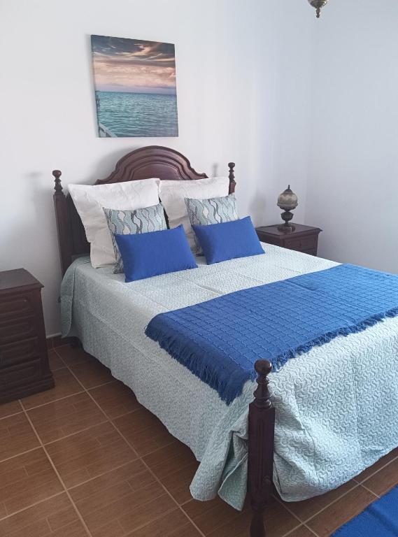 a bedroom with a bed with blue sheets and pillows at Casa Afonso Guesthouse in Ferrel