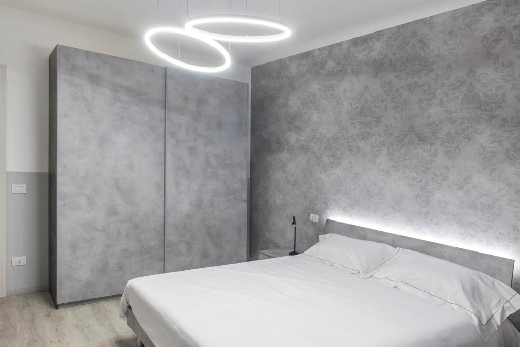 a bedroom with a white bed and a concrete wall at PETIT casa vacanze in Loreto