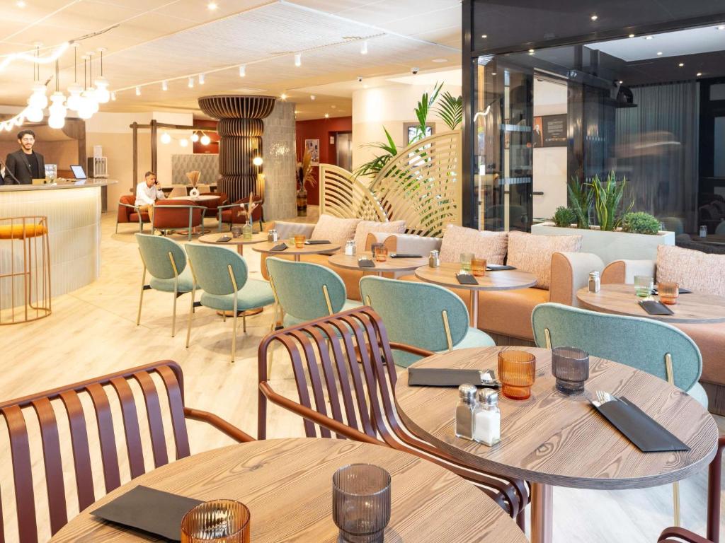 a restaurant with wooden tables and chairs and a bar at Novotel Marseille Centre Prado Vélodrome in Marseille