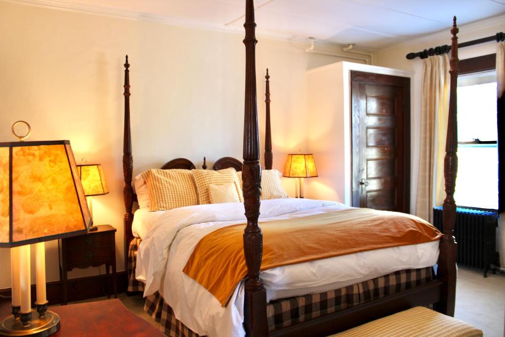 a bedroom with a four poster bed and a window at The Interlaken Inn in Lake Placid