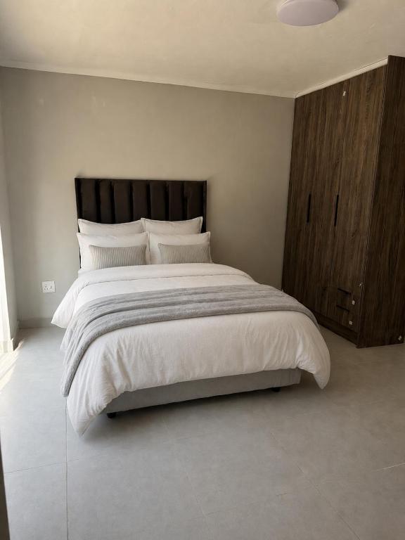 a bedroom with a large bed with white sheets and pillows at Mine Lux Rentals in Thabazimbi