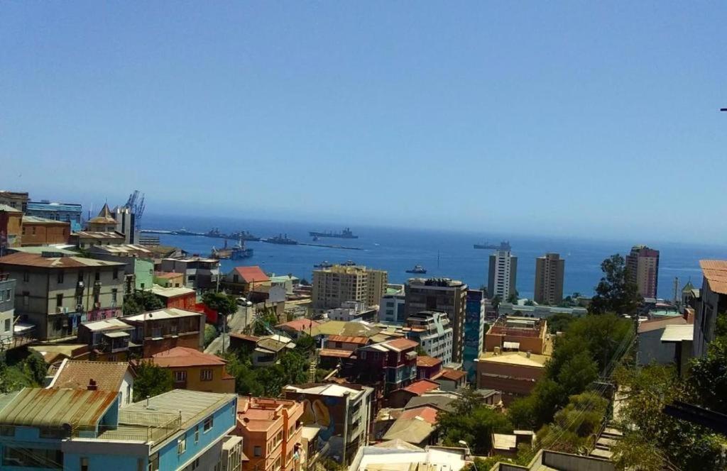 a city with buildings and the ocean in the background at Wind & Way Hostel in Valparaíso