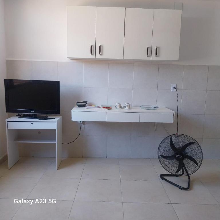 a white kitchen with a tv and a table and a chair at Hostel OS ETERNOS MONIS in Rio de Janeiro