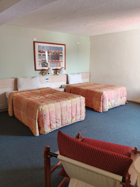 a hotel room with two beds and a red chair at Hotel Lincoln Suites in Caracas