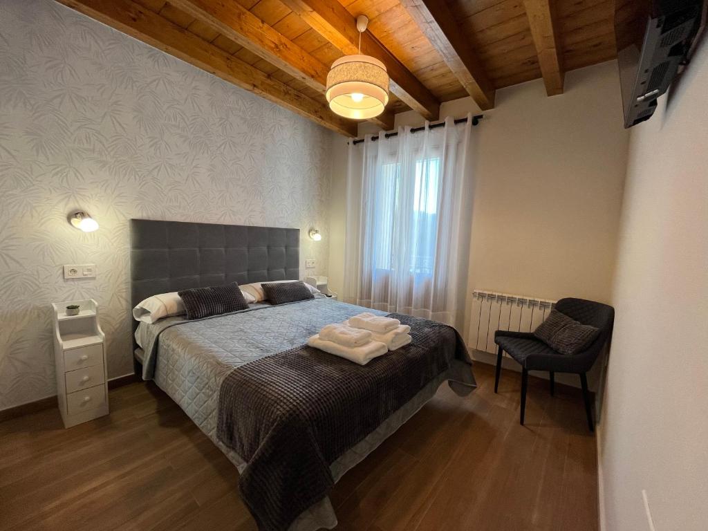 a bedroom with a large bed and a chair at Apartamentos Miguel 2 in Onís