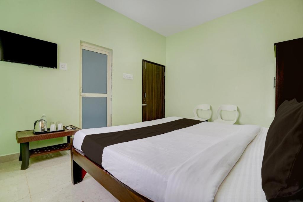 a white bedroom with a bed and a television at Hotel O Dhauli Inn in Pānchagān