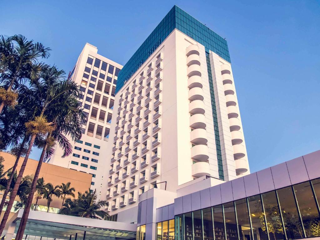 a large building with palm trees in front of it at Mercure Uberlândia Plaza Shopping in Uberlândia