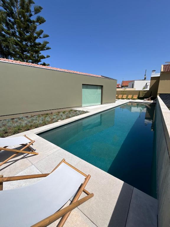 a swimming pool with two chairs and a house at Dovecote Houses in Viana do Castelo