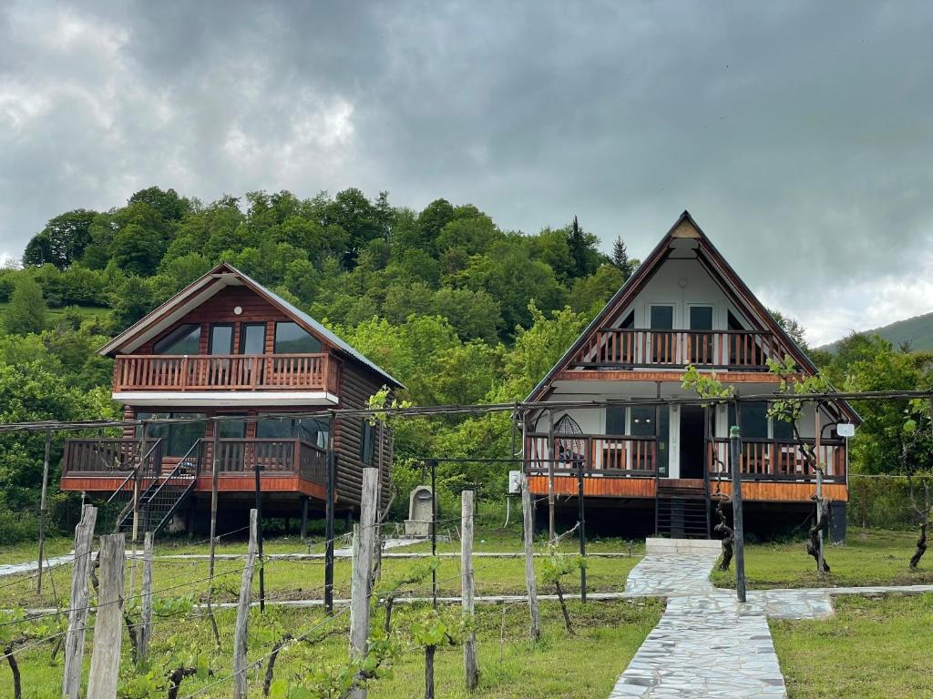 two log homes in a field with trees at Racha Hills in Ambrolauri