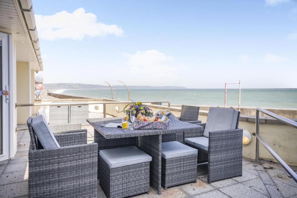a table and chairs on a balcony with the ocean at 2 Bed in Torcross oc-bcatbe in Torcross
