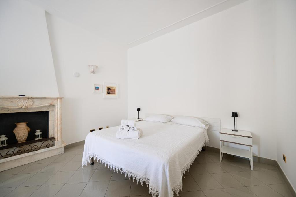 a white bedroom with a bed and a fireplace at B&B Soldano in Peschici