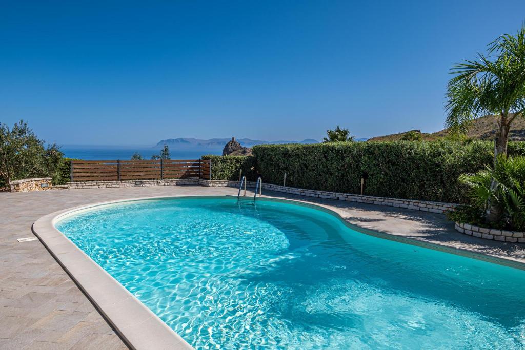 a swimming pool with blue water in a yard at Villa Torre del Mare in Scopello