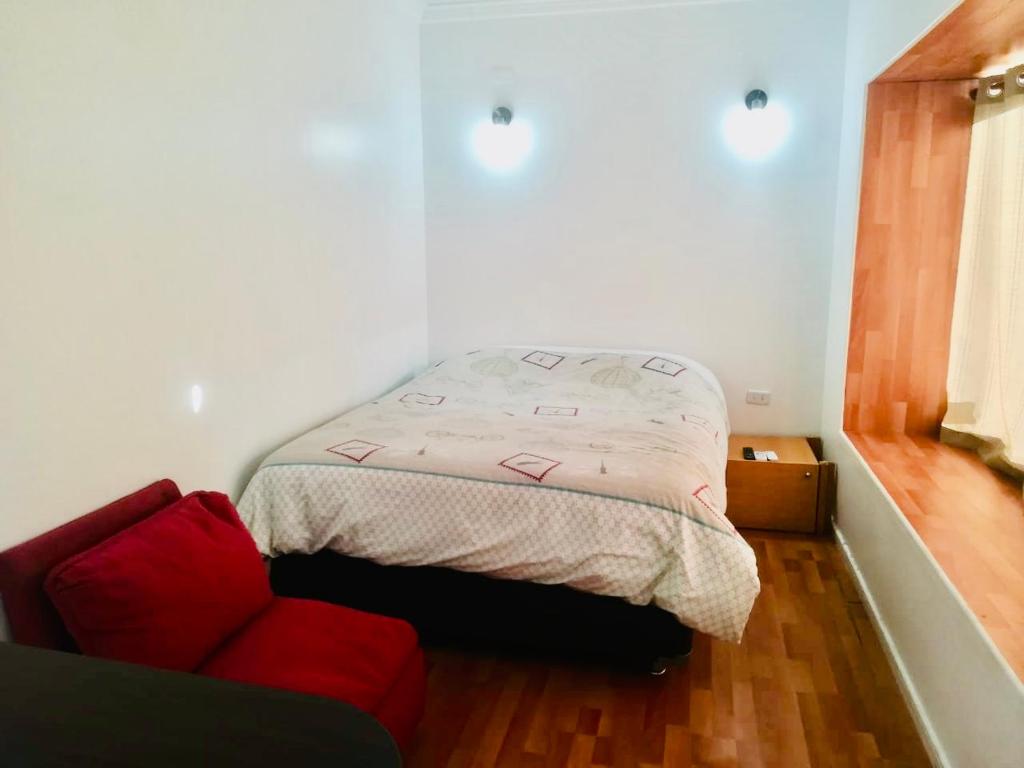 a small bedroom with a bed and a red couch at Alojamiento Cabañas in Pucón