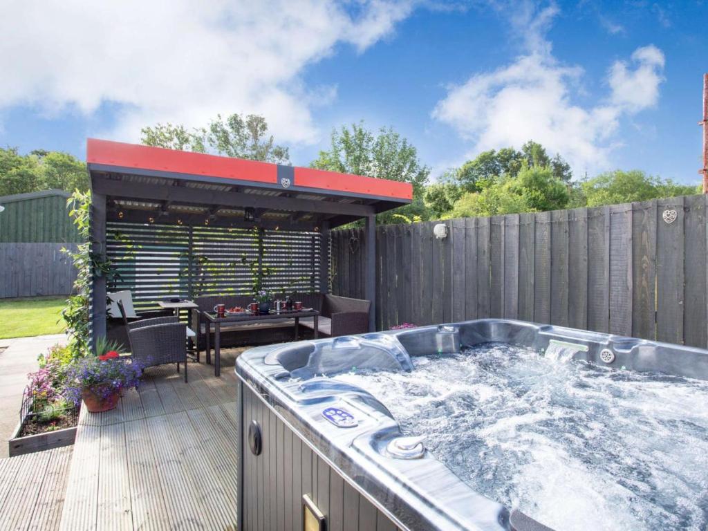 a large hot tub on a deck with a table at 2 Bed in Inverness oc-44481 in Drumnadrochit
