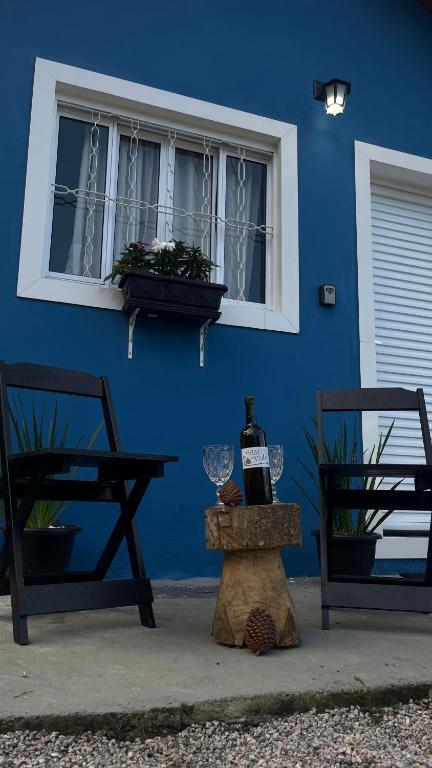 a blue building with two chairs and a window at Chale Azul Aconchegante com lareira no bosque e estacionamento grátis in Extrema
